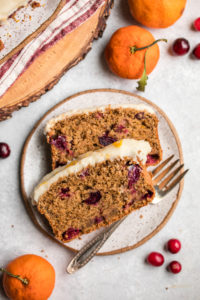 close up photo of cranberry orange bread on small white plate on gray background