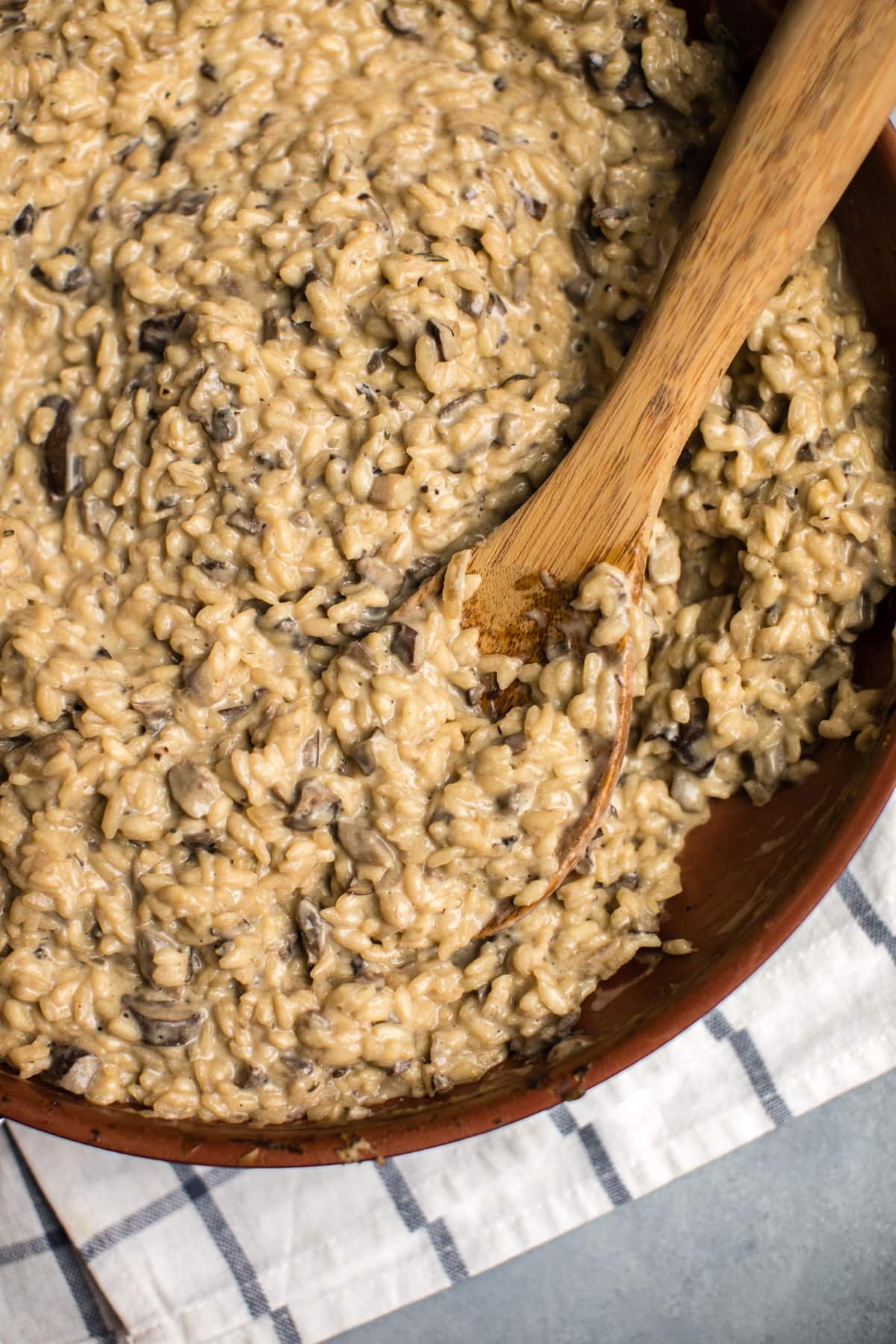 photo of cooked mushroom risotto in large copper pan with wooden spoon
