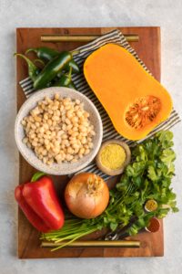 ingredients for butternut squash & white bean chili on wood serving tray