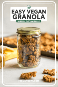 Golden baked vegan granola in glass har with baking sheet of granola in the background