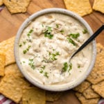 vegan french onion dip with parsley and black pepper in white speckled bowl