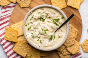 vegan french onion dip with parsley and black pepper in white speckled bowl