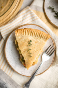 slice of chickpea pot pie topped with fresh thyme on white speckled plate