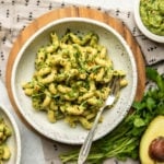 white speckled bowl filled with pesto pasta and topped with fresh basil