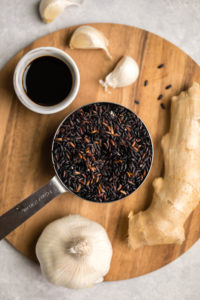 ingredients for teriyaki black rice arranged on round wooden cutting board