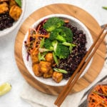 black rice bowl on round wooden cutting board with wooden chopsticks