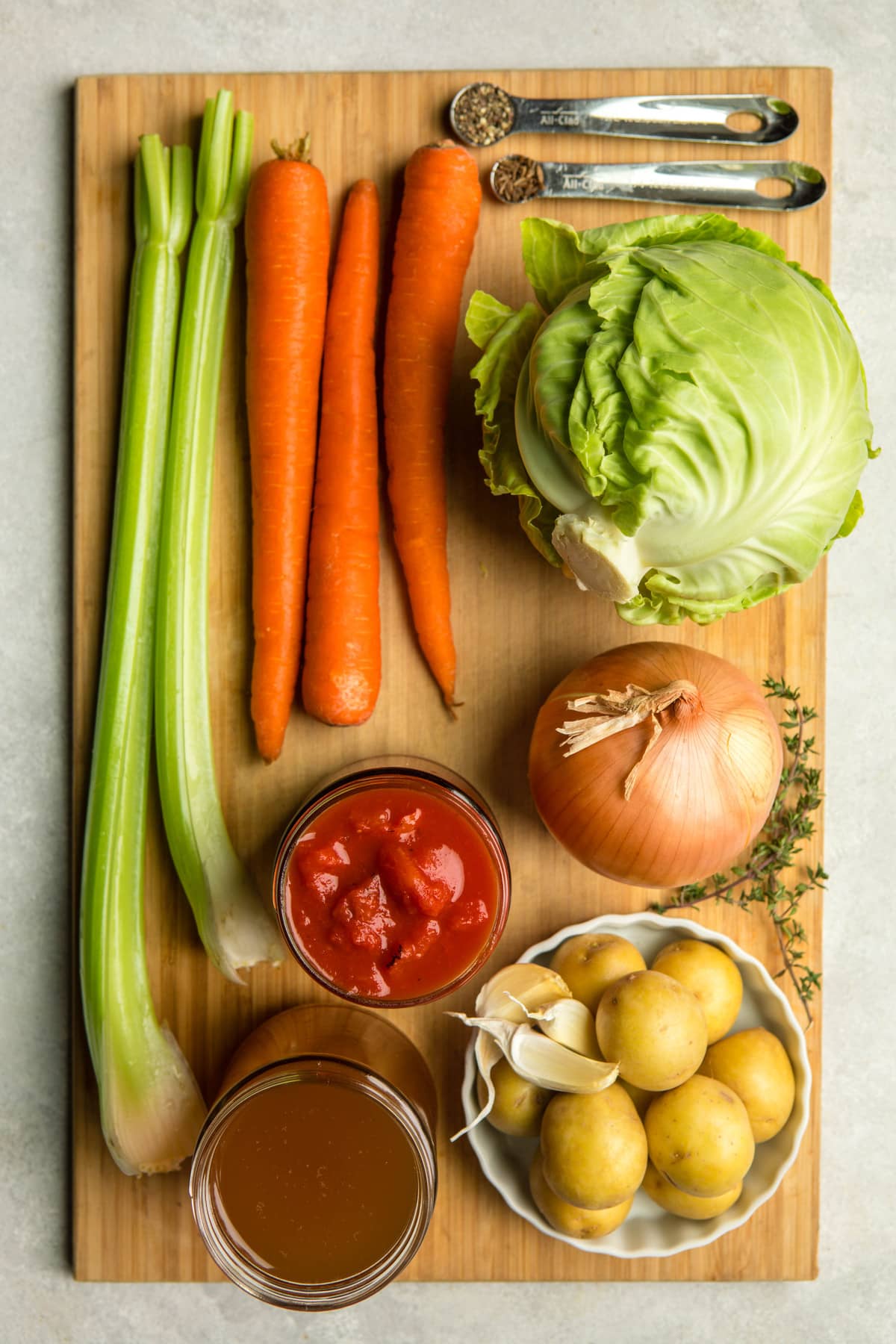 ingredients for cabbage soup on long tan wooden cutting board