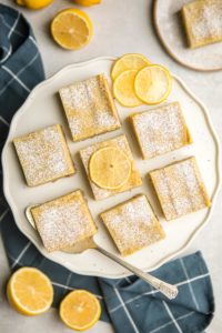 overhead shot of vegan lemon bars on round speckled white serving tray