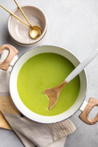 large white pot of pea soup with wooden spoon