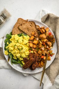 savory breakfast plate with toast, tofu scramble, tempeh bacon, and breakfast potatoes