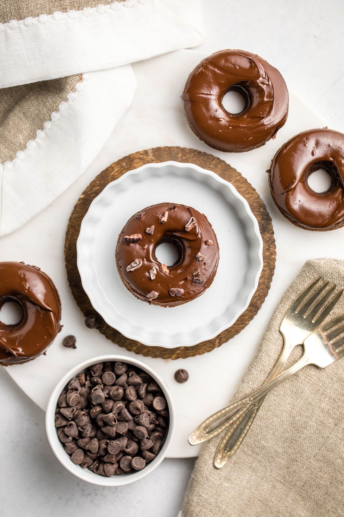 chocolate covered chocolate donuts arranged on white background with bowl of chocolate chips