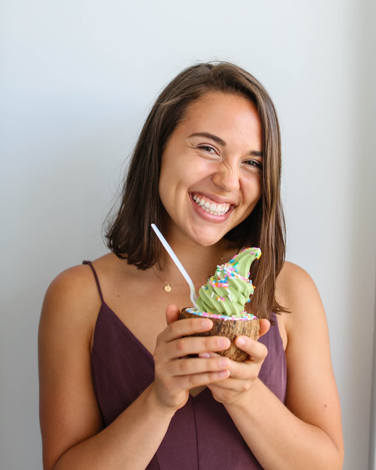 photo of caitlin smiling and holding matcha soft serve in coconut bowl