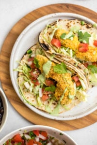 close up photo of crispy baked avocado tacos on white speckled plate