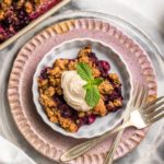 berry crumble in white dish topped with coconut yogurt and mint