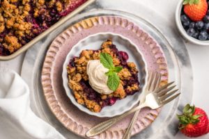 berry crumble in white dish topped with coconut yogurt and mint