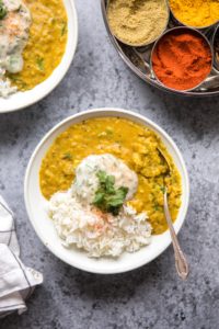 close up photo of bowl of lentil dal with indian spice kit in background