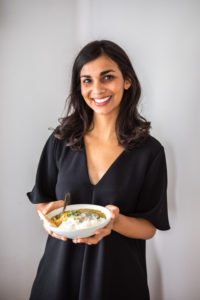 Nisha smiling while holding bowl of Dal Tadka