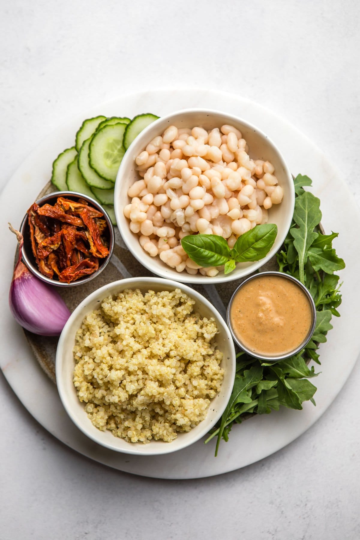 ingredients for quinoa & arugula salad on round white serving platter