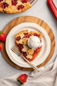 slice of strawberry rhubarb pie with scoop of vanilla ice cream
