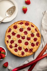 cooked strawberry rhubarb pie on gray background