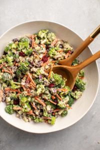 tossed broccoli salad in large white bowl on dark gray background