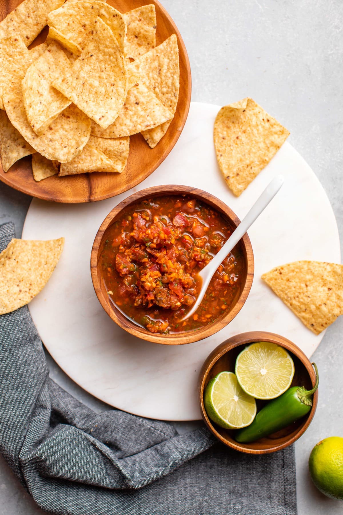 wood bowl of salsa with plate of chips and fresh lime wedges