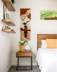 wooden bed, side table, and three floating shelves decorated in a peach, yellow, and white color scheme