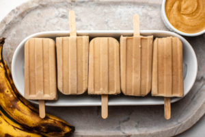 peanut butter banana popsicles arranged on white serving tray