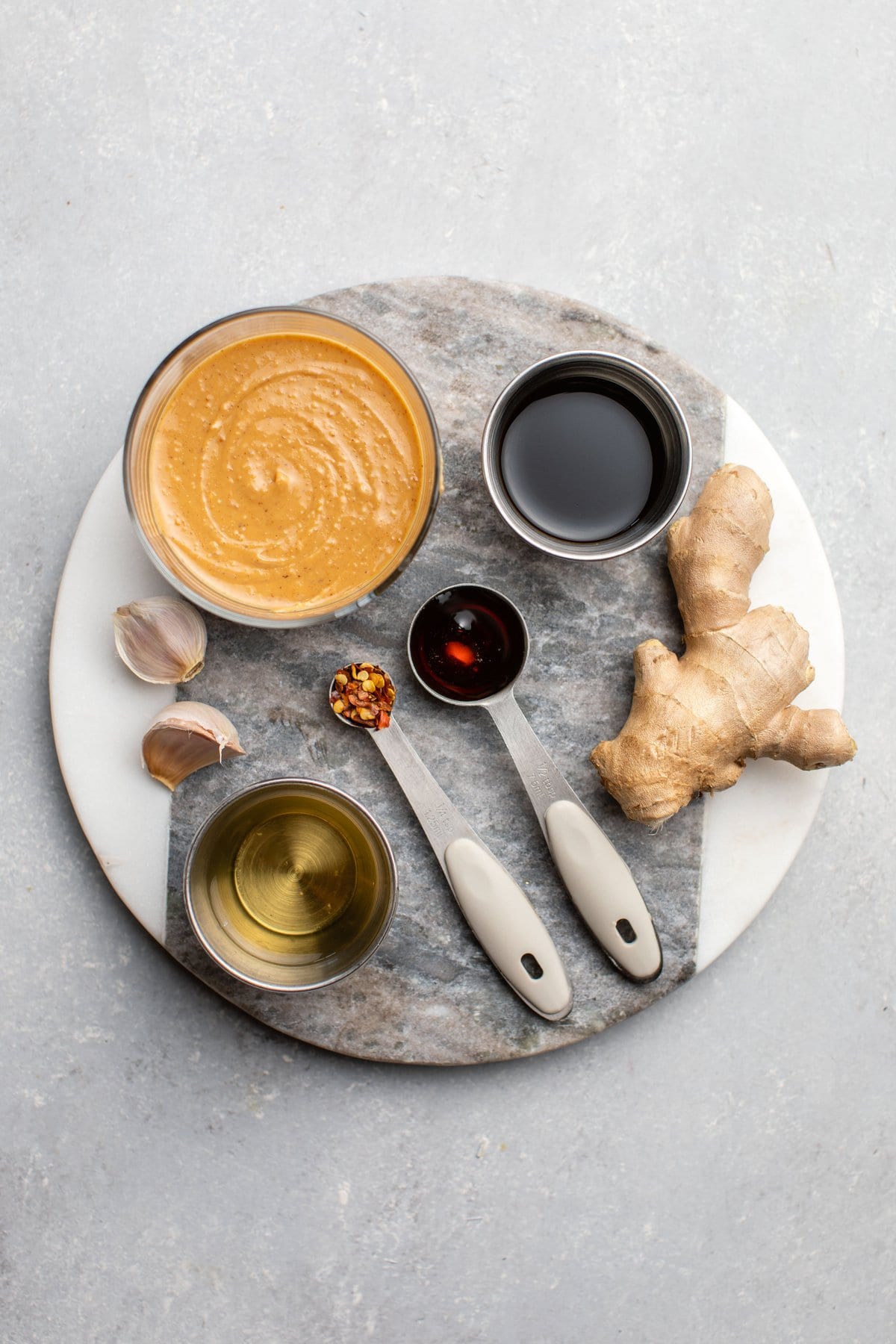 ingredients for spicy peanut sauce on round marble cutting board