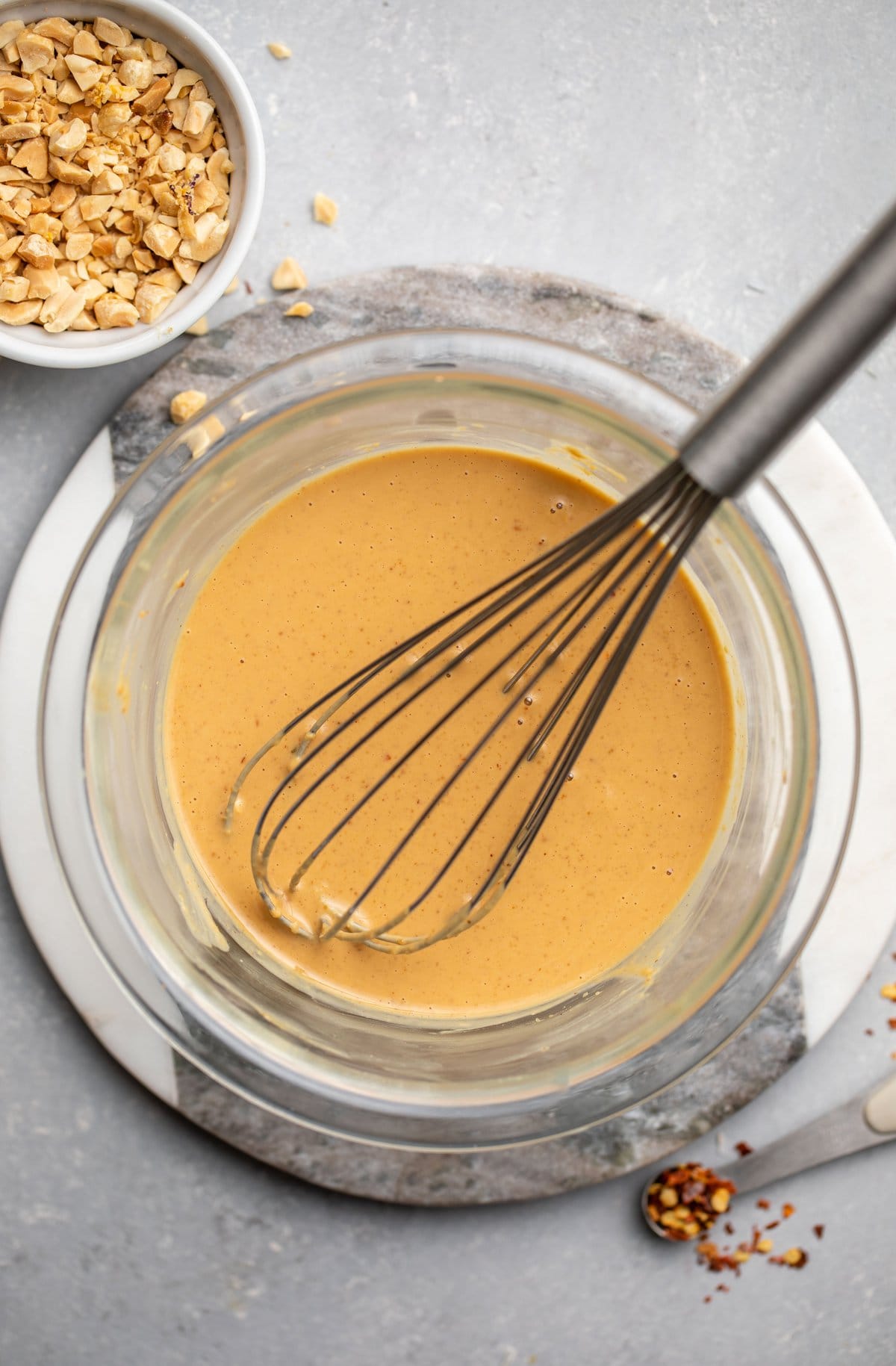 peanut sauce in large glass bowl with whisk