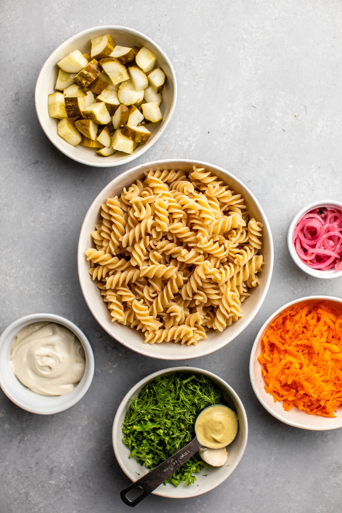 ingredients for dill pickle pasta salad in white bowls
