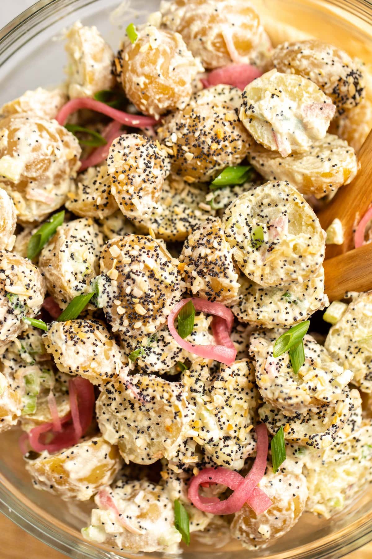 close up photo of potato salad topped with everything bagel seasoning and picked red onions