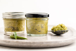two jars of thai green curry paste on stone serving tray