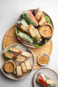 two bowls of rice paper rolls with peanut sauce