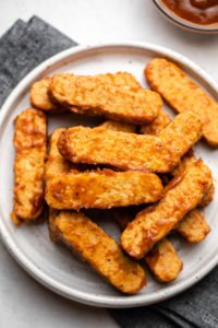close up image of bbq tempeh on white plate with navy napkin