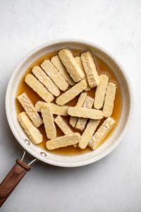 chopped tempeh and vegetable broth in small white pan