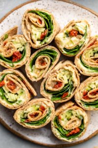 close up overhead shot of hummus pinwheels on speckled white plate