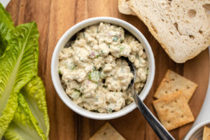 tempeh tuna salad in small white bowl on wood serving board