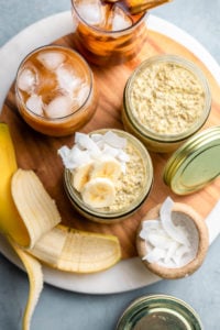 thai tea overnight oats in glass jars topped with banana and coconut