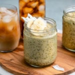 glass jars of thai tea overnight oats on wood serving tray with glass of thai tea in the background