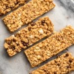 3 flavors of chewy granola bars arranged diagonally on a round marble cutting board