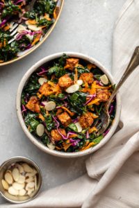 kale salad in serving bowl topped with crispy tempeh