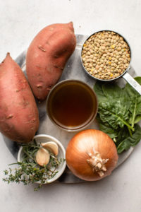 ingredients for sweet potato & lentil soup arranged on marble cutting board