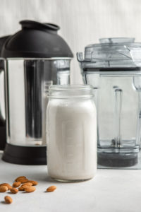 jar of almond milk in front of the vitamix and almond cow