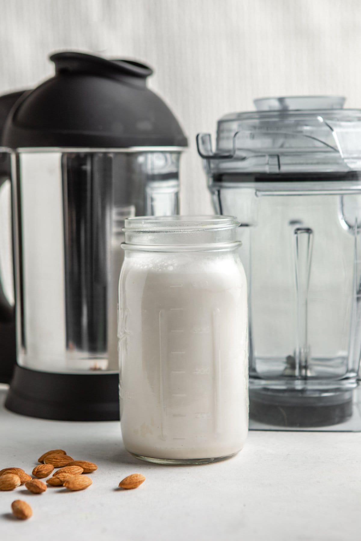 jar of almond milk in front of the vitamix and almond cow