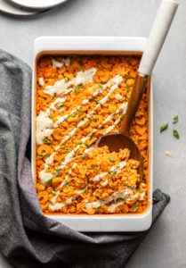 buffalo cauliflower and chickpea casserole topped with a drizzle of ranch and green onions