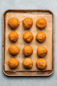 pumpkin truffles rolled into balls on small baking tray lined with parchment paper
