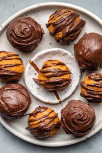 chocolate covered pumpkin truffles on white speckled plate