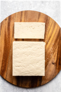 block of extra firm tofu on round cutting board