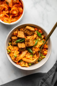 kimchi fried rice topped with crispy tofu in grey bowl on marble background